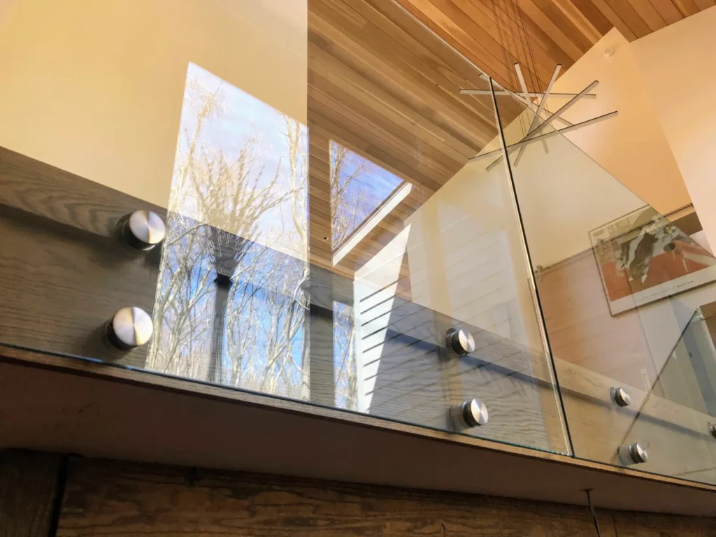Interior glass balcony railing secured with round stainless steel standoffs