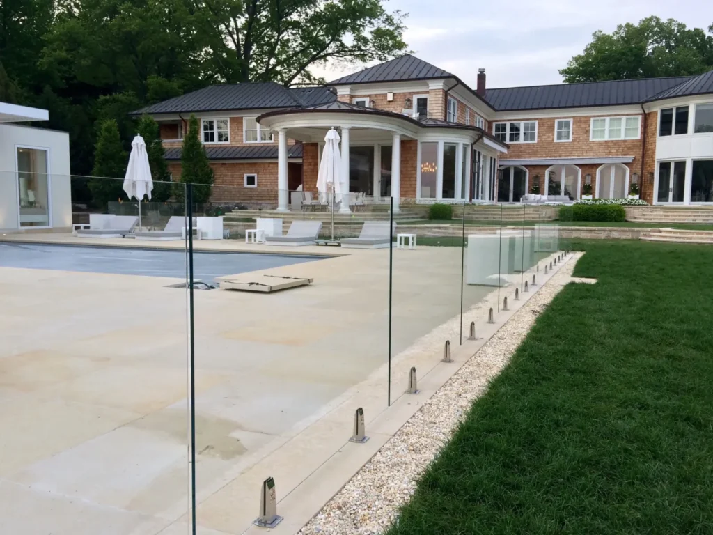 Luxury estate swimming pool enclosed with frameless glass fencing and stainless steel spigots