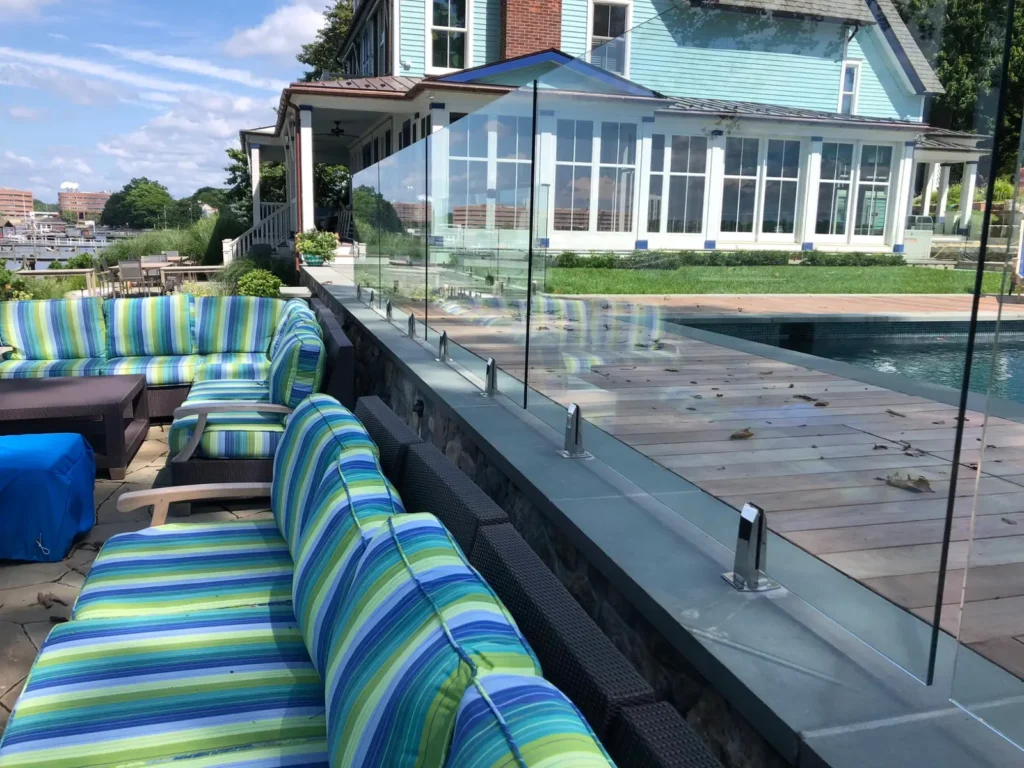 Waterfront glass pool fence beside colorful outdoor seating